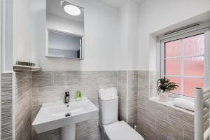a bathroom with a white toilet and a sink at Detached House in Brooklands - Prime Location - Driveway Parking, Self-Check-In, Fast WiFi and Smart TV by Yoko Property in Milton Keynes +12 photos
