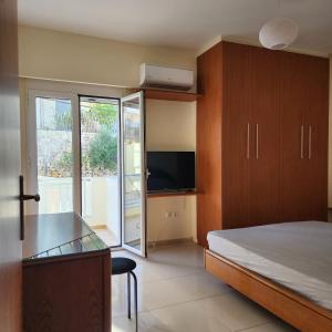 a bedroom with a bed and a desk and a television at Elevate Blue Apartment in Rethymno Town