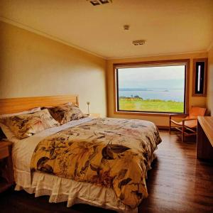 a bedroom with a large bed and a large window at Hotel Nubes de Quinchao in Quinchao
