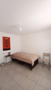 Bett in einem Zimmer mit Stuhl in der Unterkunft Departamento a metros del Parque Central de Mendoza in La Cieneguita