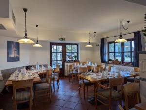 ein Restaurant mit Holztischen und -stühlen und Fenstern in der Unterkunft Charlottenhaus in Kühndorf