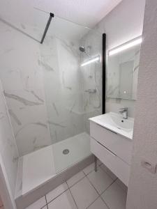 een witte badkamer met douche en wastafel bij Front de mer, 8min du Palais des Festivals in Cannes