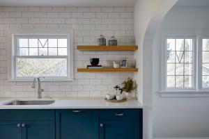 a kitchen with blue cabinets and two windows at Luxe 220, Unit 2 - Front Street Suite in Wilmington