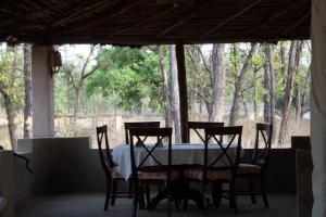 a table and chairs in a porch with trees at Atulya Kanchi Camp Bandhavgarh in Tāla