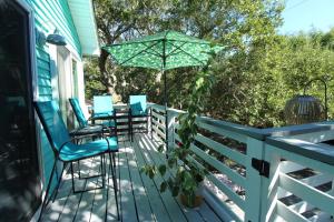 a porch with blue chairs and an umbrella at Flip Flop Casual in Folly Beach