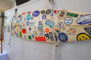 a surfboard covered in stickers on a wall at Flip Flop Casual in Folly Beach +24 photos