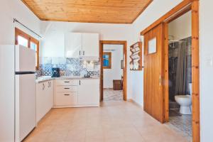 a kitchen with white cabinets and a toilet at Kouri Traditional House in Karpathos Town
