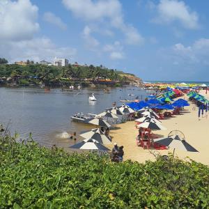 a beach with umbrellas and a boat in the water at FLAT BRISA do MAR in Pitimbu