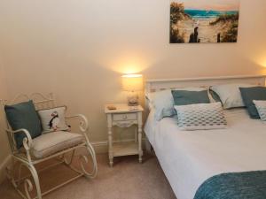 a bedroom with a bed and a chair and a lamp at Bonnie's Retreat in Amble