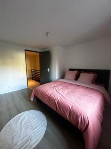 a bedroom with a large bed with a pink blanket at Charmante Maison in Abrest