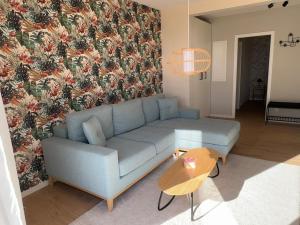 sala de estar con sofá azul y pared de flores en Auszeit am Schwielowsee - Moderne Ferienwohnung direkt am Schwielowsee, en Schwielowsee 22 fotos más