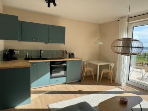Una cocina con gabinetes azules y una mesa con sillas. en Auszeit am Schwielowsee - Moderne Ferienwohnung direkt am Schwielowsee, en Schwielowsee