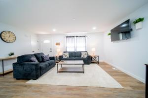 a living room with two couches and a clock at Southern Serenity Cottage in Wendell