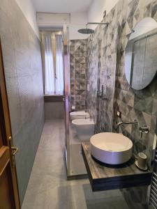 ein Badezimmer mit Waschbecken, Toilette und Spiegel in der Unterkunft The Apartment in Rom