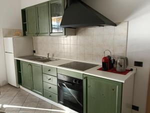 a kitchen with green cabinets and a stove top oven at Casa Arcobaleno apartments-Room holiday home in Diano dʼAlba