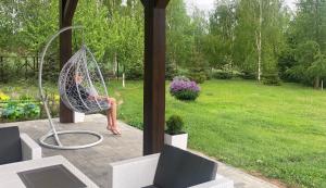 a woman sitting in a hammock in a yard at Uroczy duży dom nad jeziorem z prywatną przystanią in Steklinek