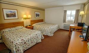 Una habitación de hotel con dos camas y un televisor. en Westgate Inn, en Coudersport