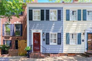 a white house with a red door and black shutters at The Cavalier in Alexandria