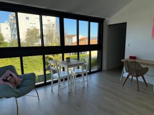a living room with a table and chairs and large windows at Poolside Retreat in Le Bouscat in Le Bouscat