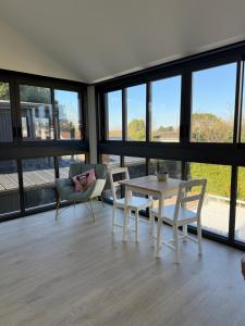 a living room with a table and chairs and windows at Poolside Retreat in Le Bouscat in Le Bouscat +2 photos