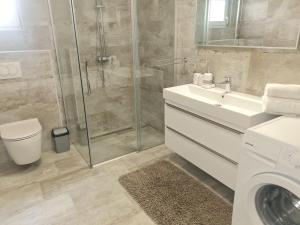 a bathroom with a shower and a sink and a washing machine at Manta in Lukovo Šugarje +16 photos