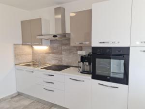 a white kitchen with a sink and a microwave at Manta in Lukovo Šugarje