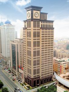 un grand bâtiment avec une tour d'horloge en haut dans l'établissement Dalian Asia Pacific Service Apartment (Former Somerset Harbour Court Dalian), à Dalian