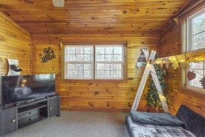 a living room with a flat screen tv in a log cabin at Bear’s Den in Sautee Nacoochee