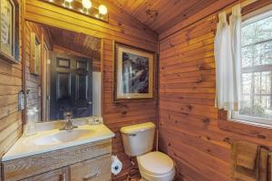 a bathroom with a toilet and a sink in a log cabin at Bear’s Den in Sautee Nacoochee +22 photos
