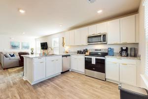 a kitchen with white cabinets and appliances and a couch at Salty Retreat in Ocean Isle Beach