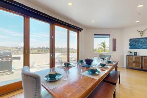 een eetkamer met een lange houten tafel en glazen ramen bij Canyon Paradise Spacious & Luxurious Retreat w/Unforgettable Views, Private Pool-close to Hiking in Encinitas