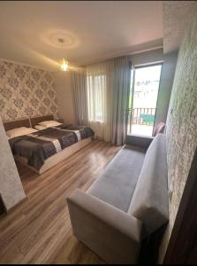 a bedroom with a bed and a couch and a window at Hotel Diamond Kazbegi in Stepantsminda