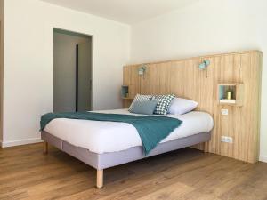 una camera da letto con un letto grande con testiera in legno di Appartement Aqua-Villas Lake And Sea a Seignosse