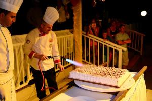 two chefs are cutting a cake with a sword at Ephesia Holiday Beach Club in Kuşadası
