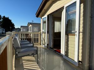 eine Veranda mit einem Stuhl und einer Glasschiebetür in der Unterkunft The Retreat 34, Central Heating, Pet friendly, WiFi - Golden Palm Resort - Meadow Lakes Caravan & Lodge Hire in Chapel Saint Leonards