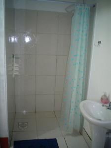 a shower with a blue shower curtain next to a sink at Sitio Preserva in São Borja