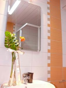 a bathroom sink with a mirror and a vase with a flower at Bella Vista Apartments in Ohrid