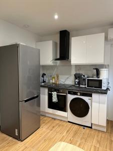 a kitchen with a stainless steel refrigerator and a dishwasher at Charmant T2 proche gare SNCF à 15 min de Lyon in Sérézin-du-Rhône