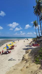 a group of people sitting on a beach with umbrellas at Flat Brisa do Mar in Pitimbu