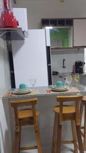 a kitchen with a counter with two stools and a refrigerator at Flat Brisa do Mar in Pitimbu