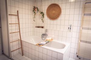 a white tiled bathroom with a tub and a sink at F I E R Huisje in Eersel