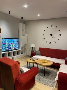 a living room with a couch and a clock on the wall at ORA-PRN,cosy apartment in the city center in Pristina