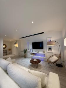 een woonkamer met een witte bank en een tv bij L'Odyssée au centre-ville in Duinkerke