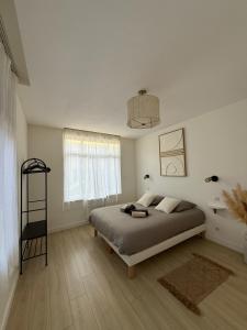 een witte slaapkamer met een bed en een raam bij L'Odyssée au centre-ville in Duinkerke