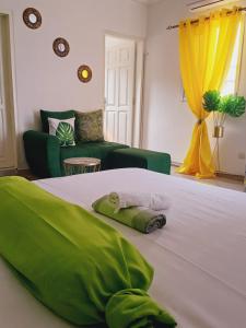 ein Schlafzimmer mit einem Bett mit grüner Bettwäsche und einer Couch in der Unterkunft Résidence Meublée Pachira I in Abidjan