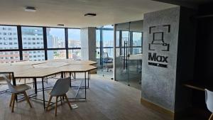 an office with tables and chairs and a large window at Loft Alto Padrão Um Quarto in Recife
