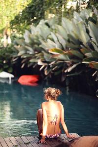 una mujer en bikini sentada en el agua en M Boutique Hostel, en Seminyak