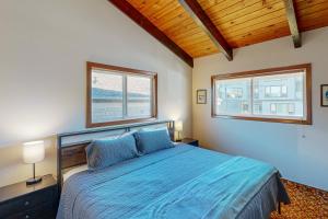a bedroom with a blue bed and two windows at Rockaway Beach Cozy Cabin in Rockaway Beach