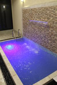 a swimming pool with purple water and a waterfall at فيلا مكونة من 3 غرف نوم و مجلس و صالة و مطبخ وغرفة عاملة و مسبح تفتح الغرف حسب عدد النزلاء in Riyadh +15 photos