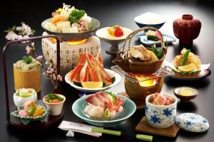 una mesa cubierta con platos de comida y cuencos de sushi en Yumotoya, en Niigata